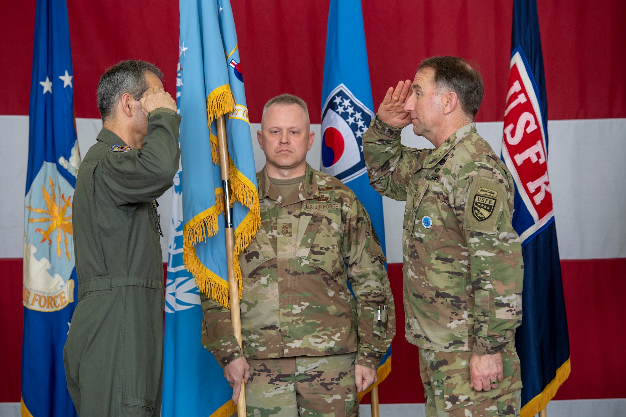 Lt. Gen. Kenneth S. Wilsbach salutes Gen. Robert “Abe” Abrams, Commander, United Nations Command/Combined Forces Command/United States Forces Korea, as Chief Master Sgt. Philip Hudson, Seventh Air Force command chief holds a flag at Osan Air Base, ROK, June 12, 2020. Due to COVID-19 mitigation restriction, no official passing of the flag was conducted. (U.S. Air Force photo by Senior Airman Darien Perez)
