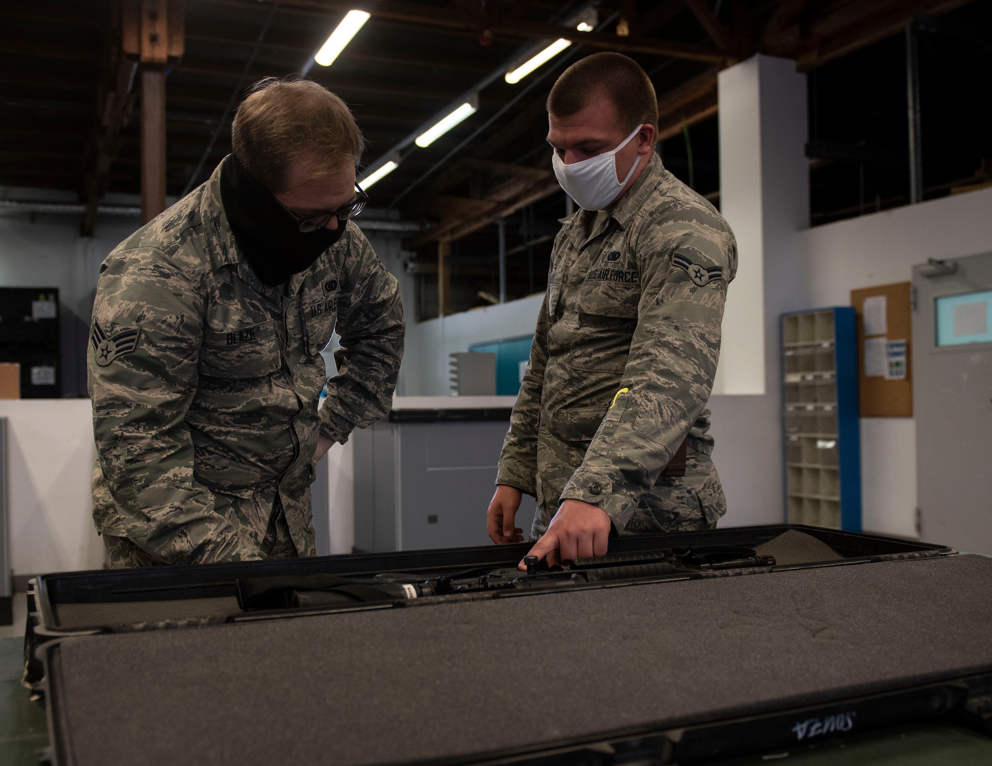 U.S. Air Force Senior Airman Michael Blaze, left, 52nd Logistics Readiness Squadron Individual Protective Equipment journeyman, and A1C Corbin Hanly, right, 52nd LRS IPE apprentice, demonstrate issuing a weapon, June 4, 2020, at Spangdahlem Air Base, Germany. The 52nd LRS IPE airmen responded to the COVID-19 pandemic by rapidly issuing protective face masks to Airmen stationed at the 52nd Fighter Wing and surrounding geographically separated units. (U.S. Air Force photo by Senior Airman Melody W. Howley)