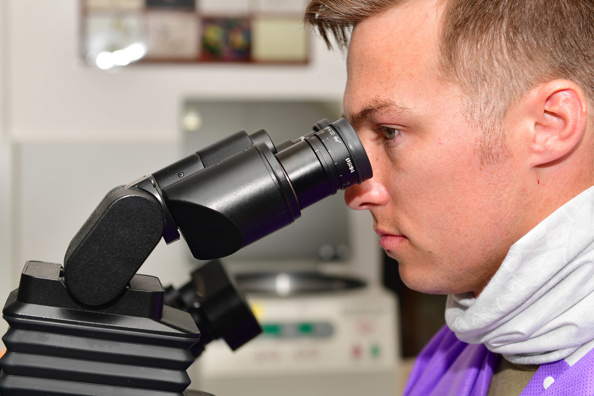 An Airman looks into a microscope.