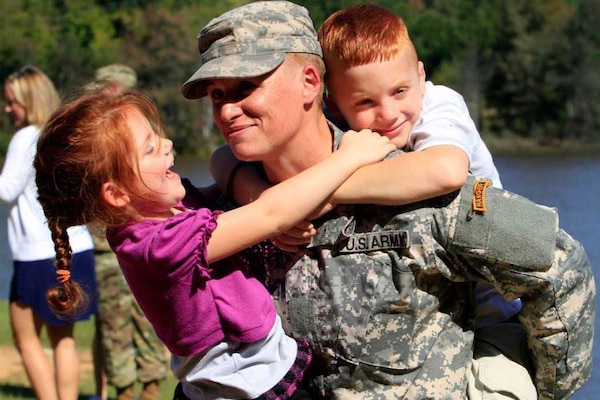 A woman in uniform plays with two young children.