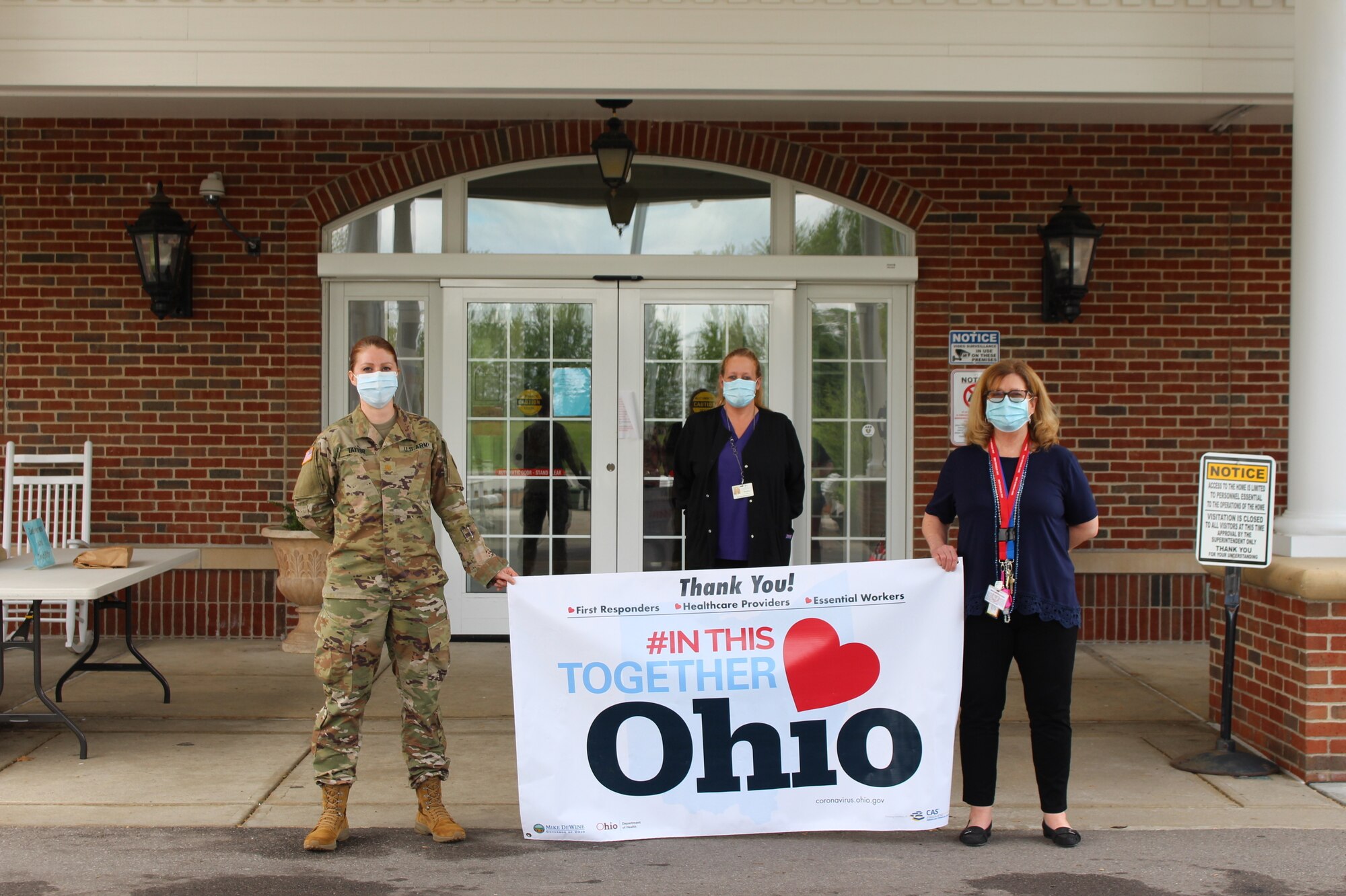 Maj. Jessica Taylor (from left), commander of Company C, 237th Support Battalion, holds an “#In This Together Ohio” banner along with Ohio Veterans Home-Georgetown staff members Heather Doss, director of nursing, and Linda Slone, the facility administrator, at the Ohio Veterans Home in Georgetown, Ohio. In support of the Ohio Department of Veterans Services, Taylor recently led a team of Ohio National Guard medical personnel that conducted COVID-19 testing at the facility and also provided a supply of personal protective equipment. (Photo courtesy of Ohio Department of Veterans Services)
