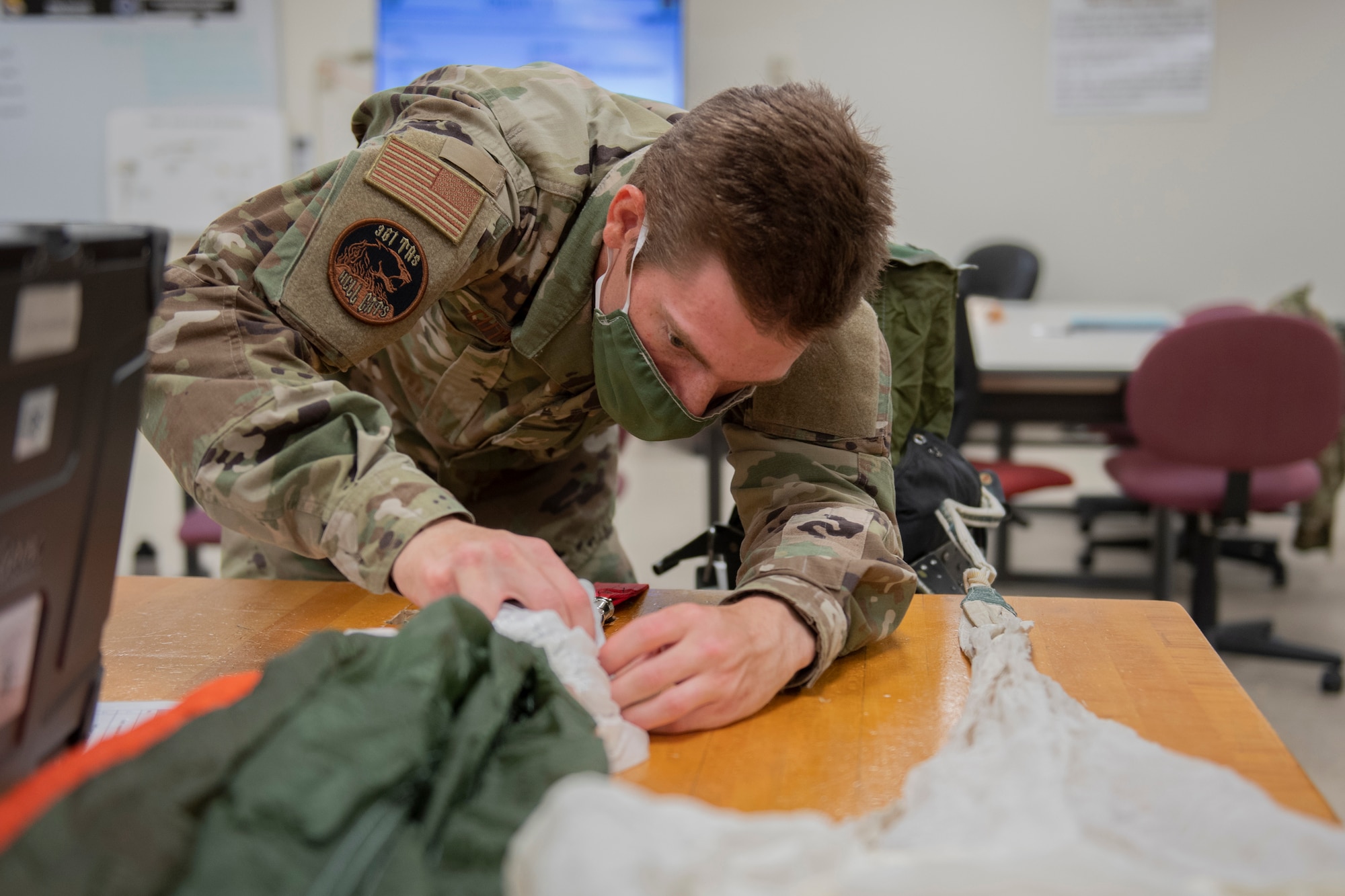 Aircrew Flight Equipment student stacks the apex of a parachute