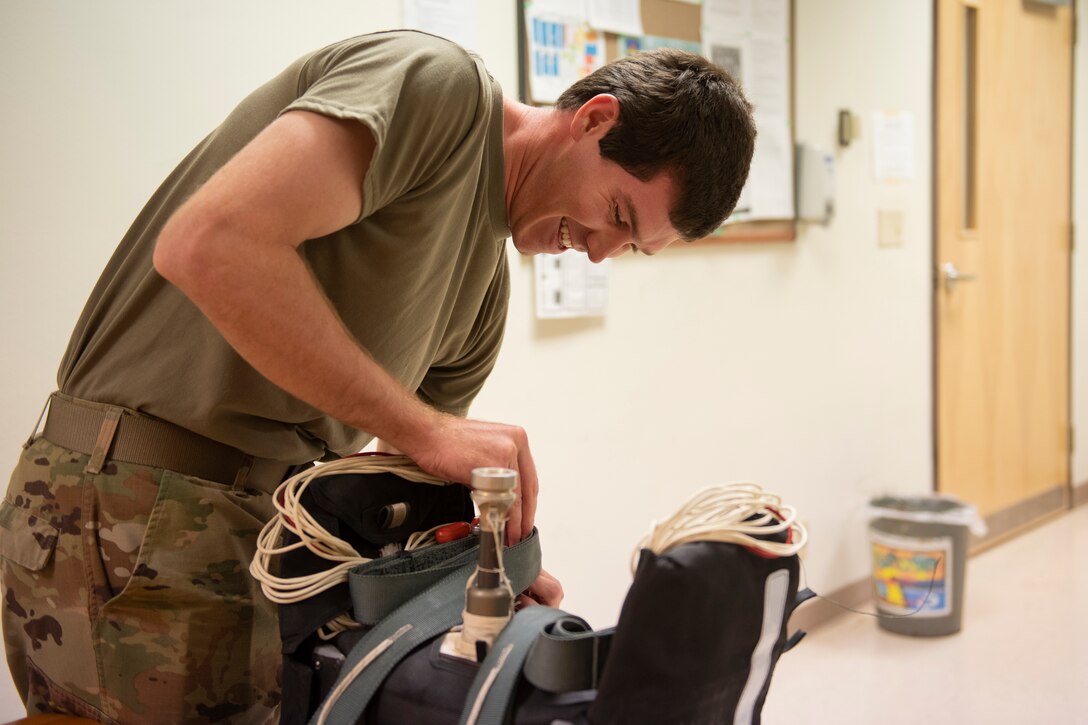 Aircrew Flight Equipment student secures ejection seat riser straps