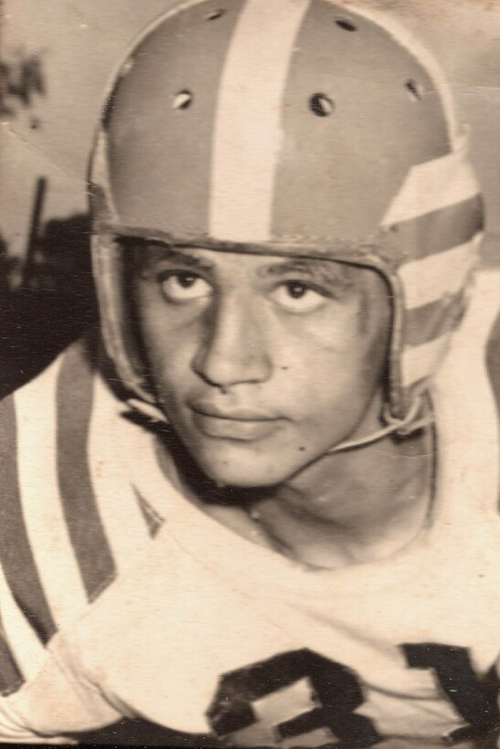 A young man wears a football helmet and jersey.