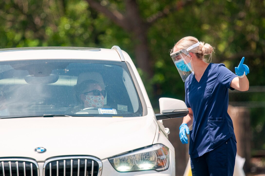 A soldier speaks to a driver through the window of a car.