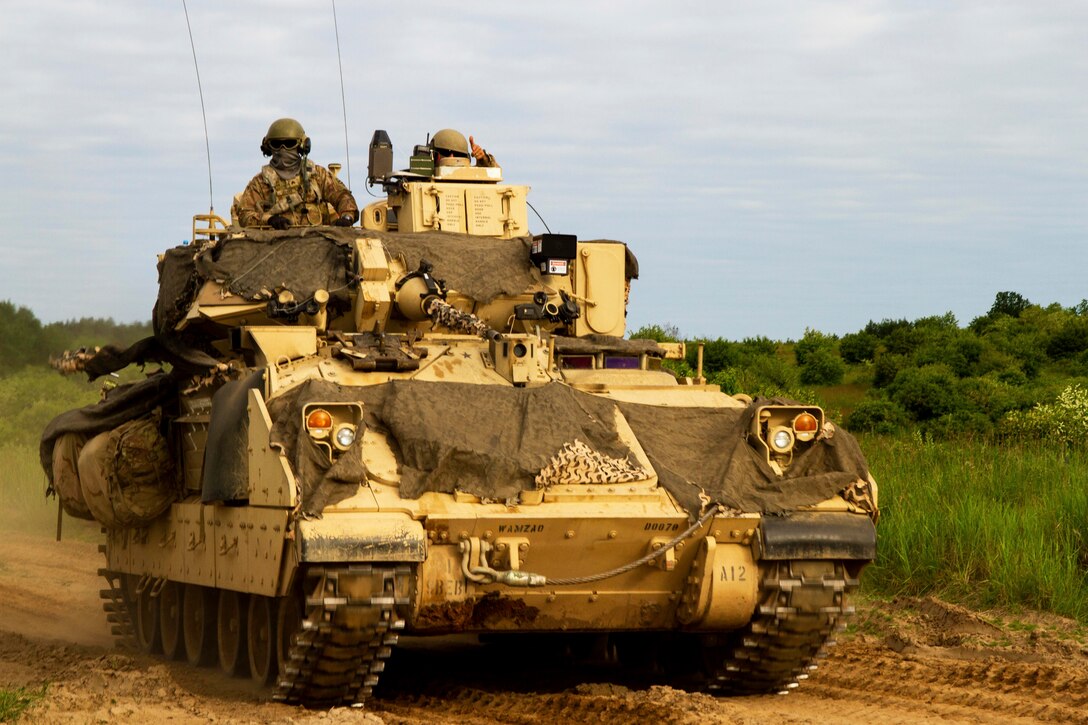 Two soldiers ride in a military vehicle.