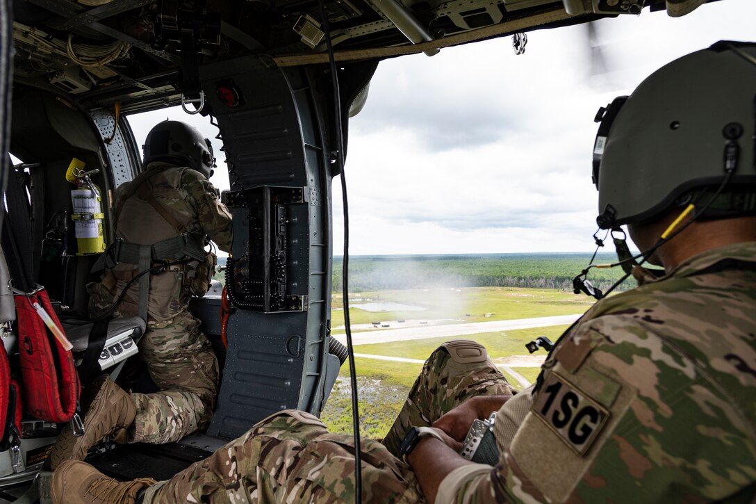 A photo of an Airman watching a special missions aviator fire an M2 machine gun