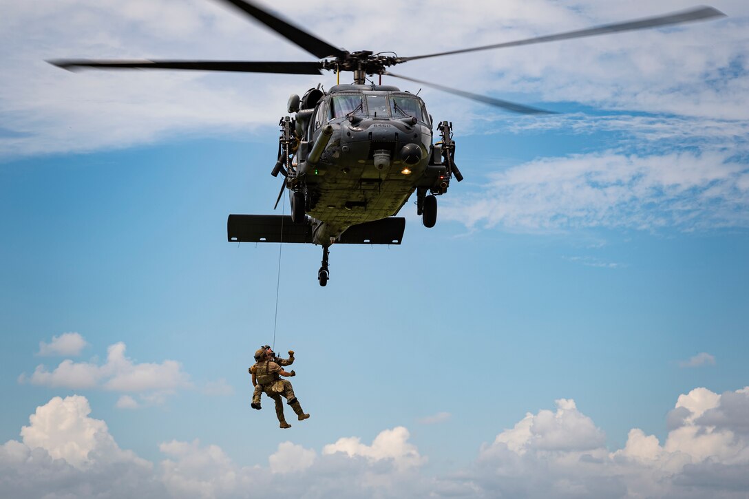 A photo of Airmen being hoisted into an HH-60G Pave Hawk