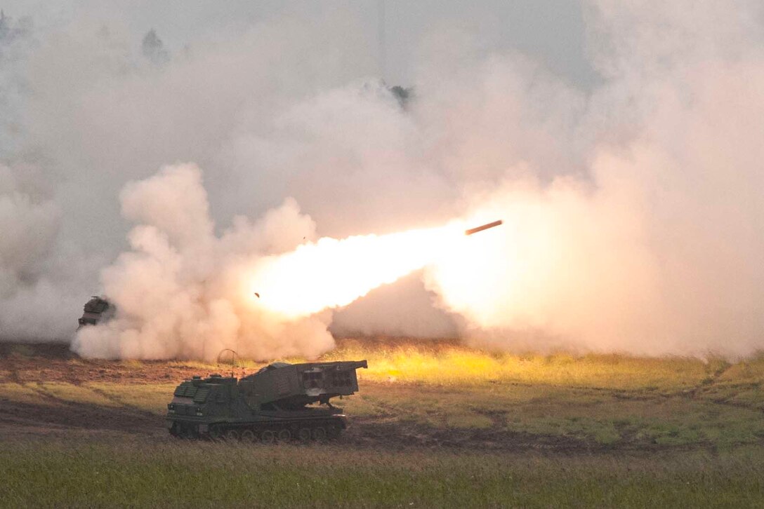 An Army vehicle fires a rocket in a smoky field.