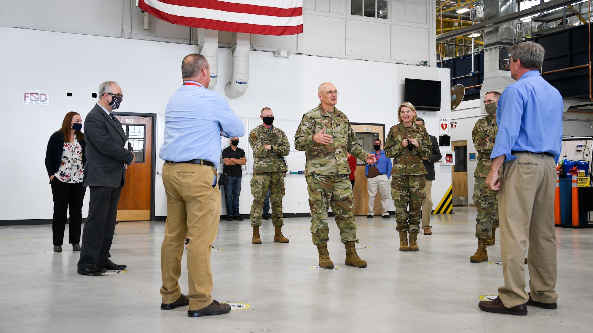 Gen. Bunch speaks with leadership standing in an aircraft maintenance hangar from the 309th Commodities Maintenance Group.