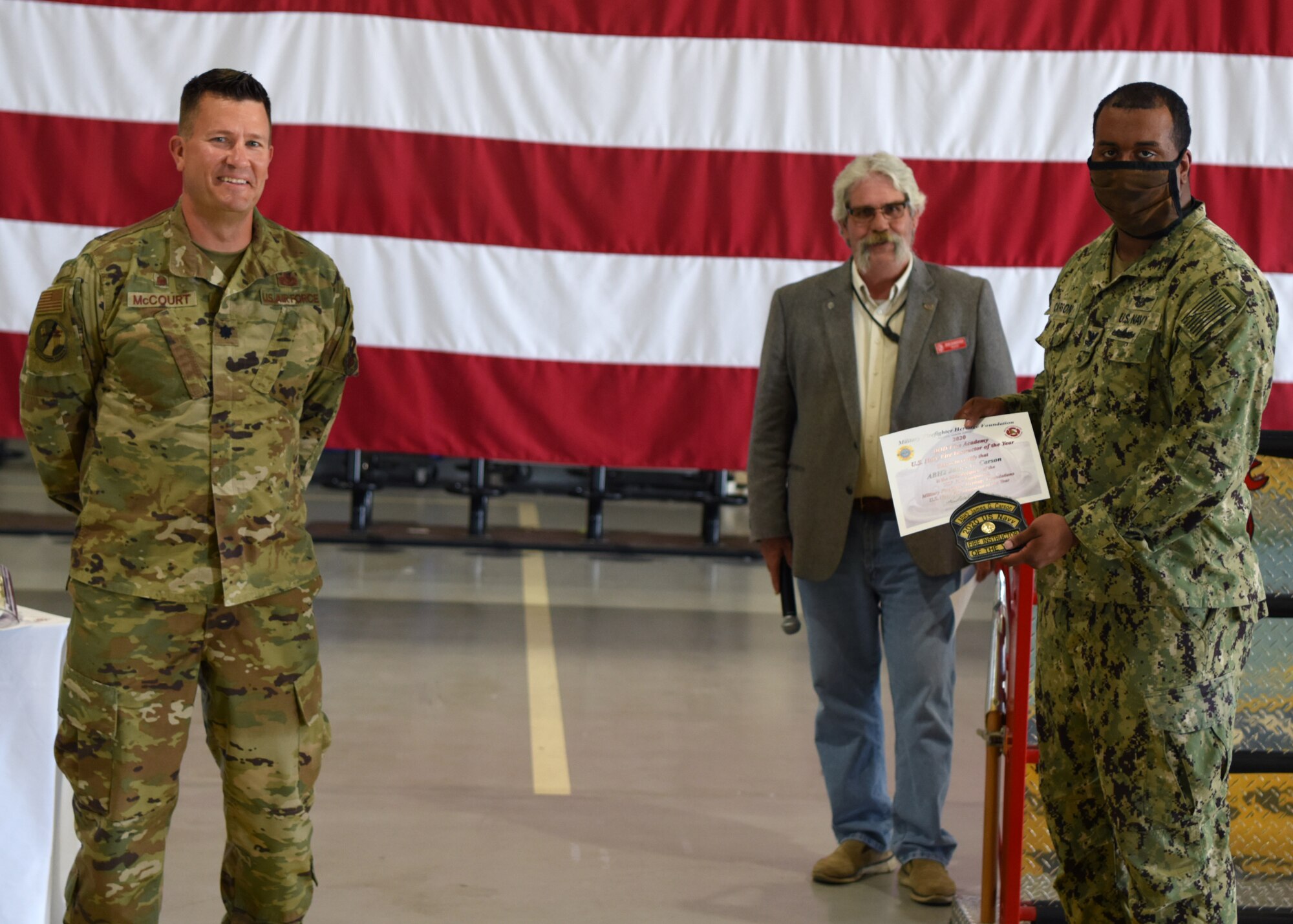U.S. Air Force Lt. Col. Michael McCourt, 312th Training Squadron commander, presents Navy Petty Officer 2nd Class James Carson, Center of Warfare Information Training detachment fire instructor, with the Department of Defense Fire Academy U.S. Navy Instructor of the Year Award at the Louis F. Garland Department of Defense Fire Academy on Goodfellow Air Force Base, Texas, June 5, 2020. Due to COVID-19, the award was presented at a distance to follow social distancing standards. (U.S. Air Force photo by Airman 1st Class Ethan Sherwood)