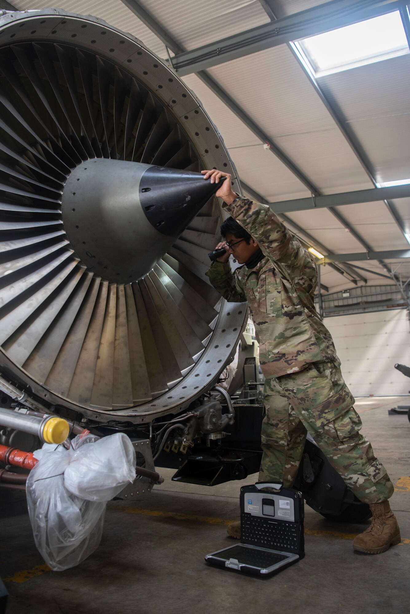 Airman 1st Class Rajendra Harilall, 100th Aircraft Maintenance Squadron aerospace propulsion journeyman, inspects the blades of an F108 turbofan engine at RAF Mildenhall, England, June 9, 2020. Maintainers frequently examine the blades for foreign object damage and to verify components can safely operate. (U.S. Air Force photo by Airman 1st Class Joseph Barron)