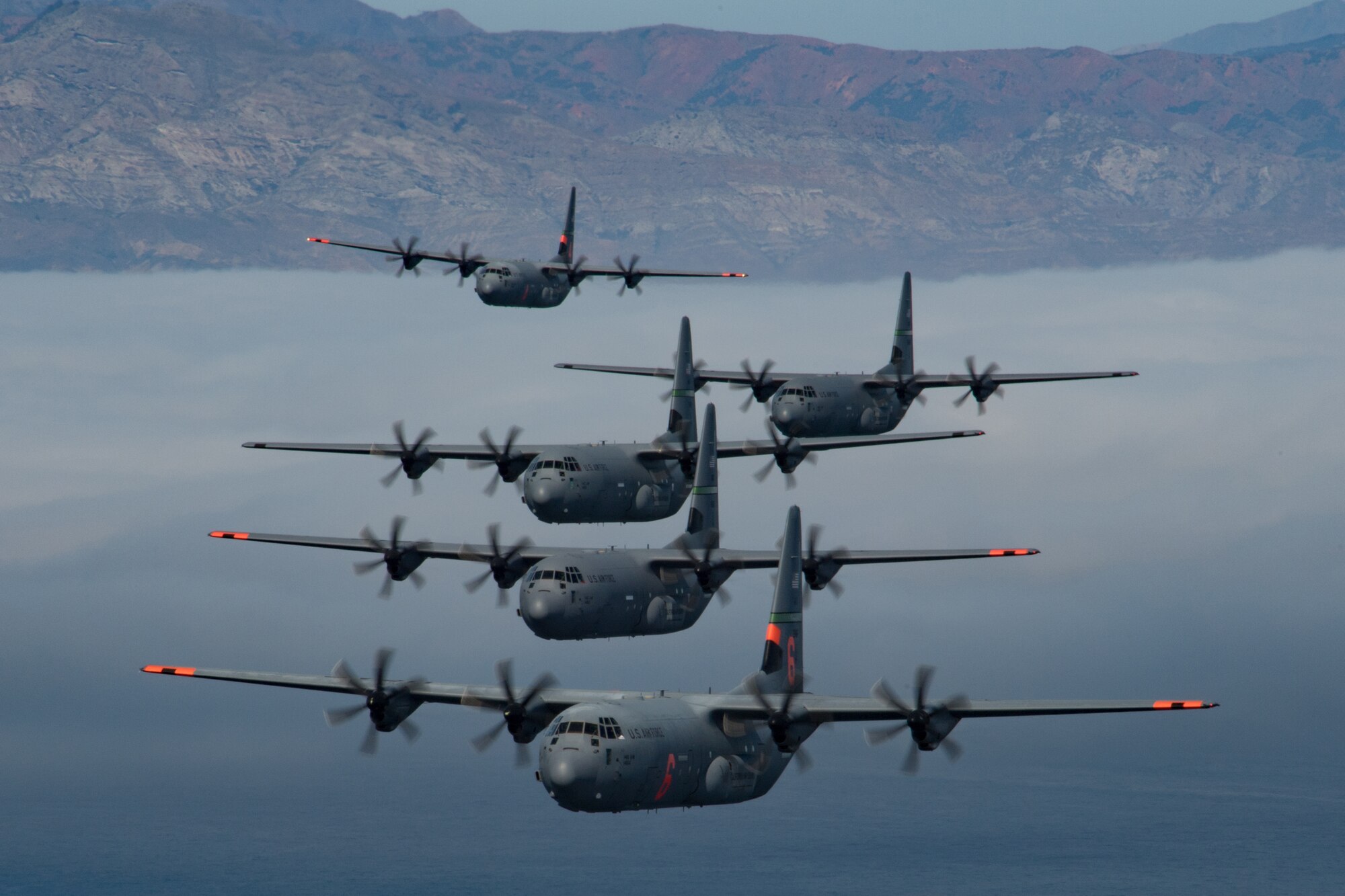 5 of 6 California Air National Guard C-130J Super Hercules aircraft fly in tight formation over the Pacific Ocean, California. May 27, 2020. California Air National Guard maintainers from the 146th Maintenance Group and aircrew from the 115th Airlift Squadron, collaborated to accomplish the launching of 6 C-130J Super Hercules aircraft for the first time in over 20 years U.S. Air National Guard by Tech. Sgt. Nieko Carzis.