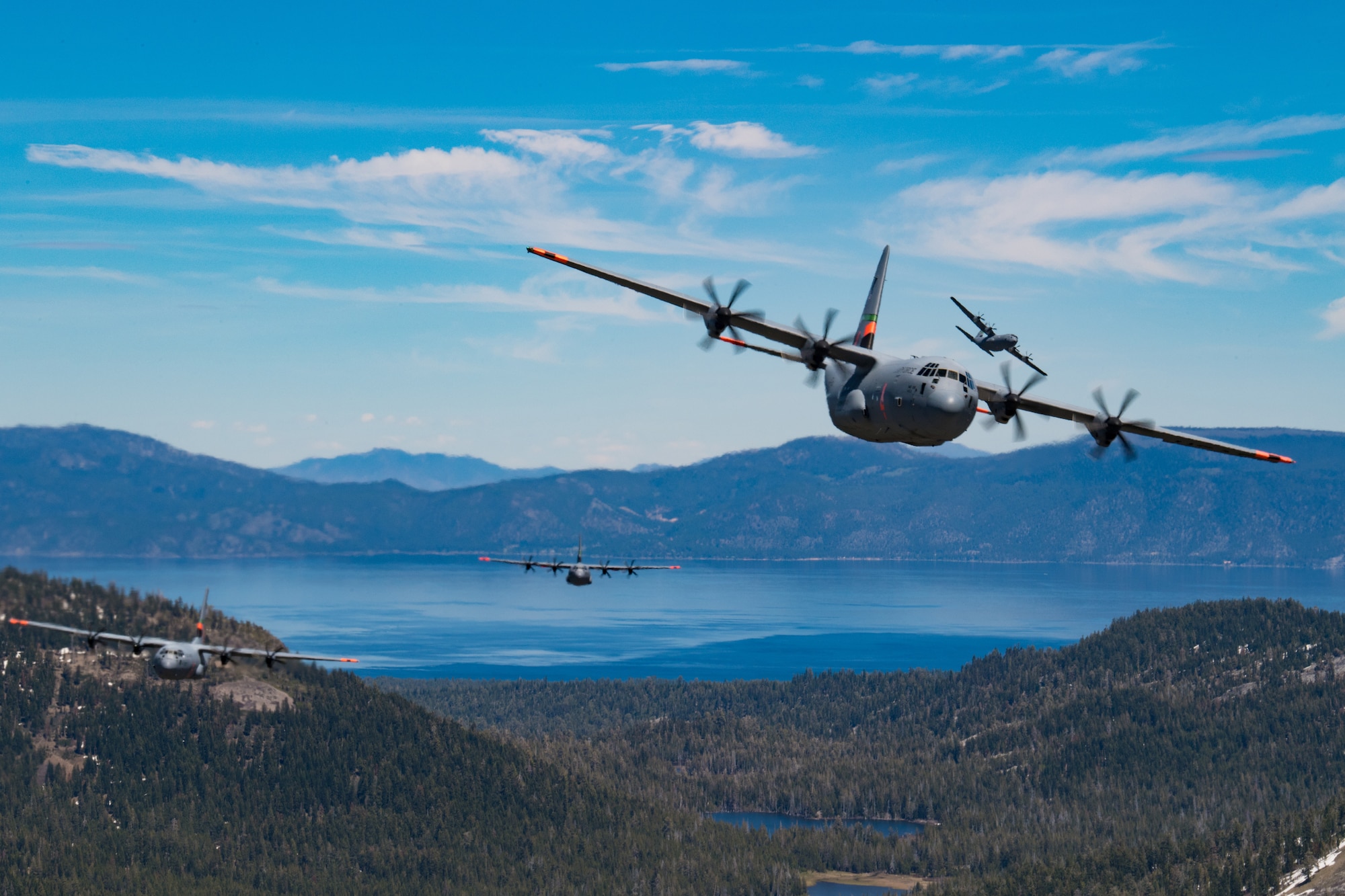 5 of 6 California Air National Guard C-130J Super Hercules aircraft fly in tight formation over the Lake Tahoe, California. May 27, 2020. California Air National Guard maintainers from the 146th Maintenance Group and aircrew from the 115th Airlift Squadron, collaborated to accomplish the launching of 6 C-130J Super Hercules aircraft for the first time in over 20 years U.S. Air National Guard by Tech. Sgt. Nieko Carzis.
