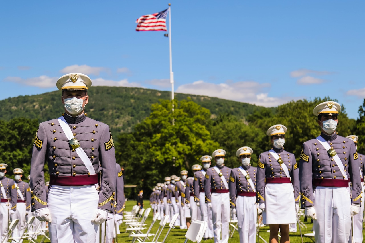 Cadets stand in formation as an American flag flutters above them.