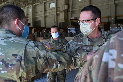 Sgt. Andrew Stock, Headquarters and Service Company, 3643d Brigade Support Battalion, bumps elbows with Gen. Joseph Lengyel, Chief of the National Guard Bureau, at the New Hampshire National Guard Army Aviation Support Facility warehouse on May 27, 2020, in Concord.