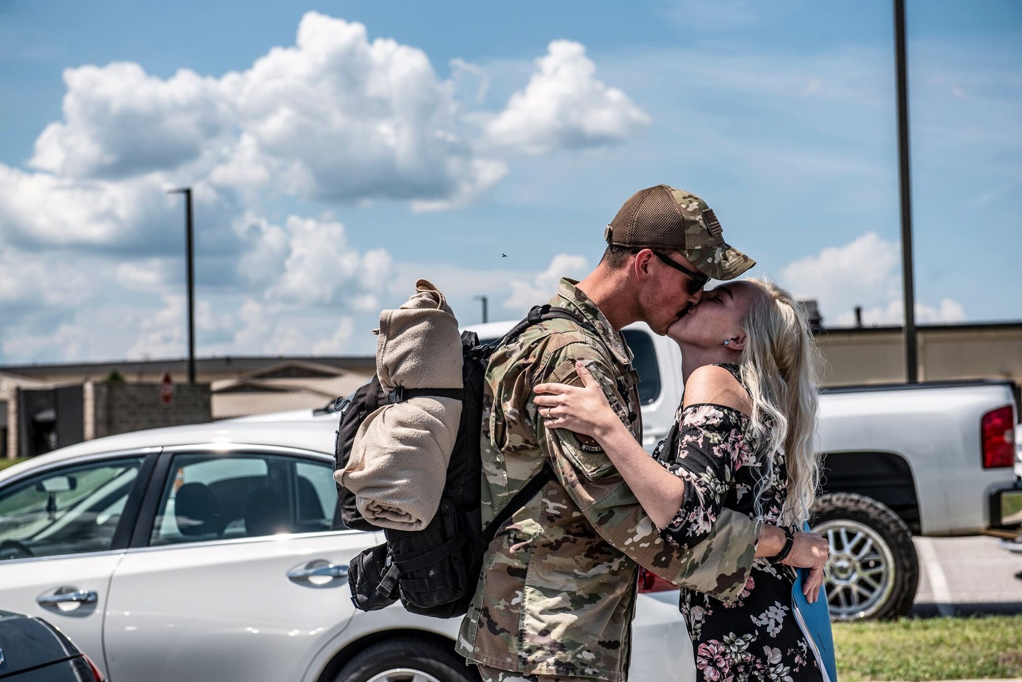 Photo of a service member kissing his spouse in a parking lot.