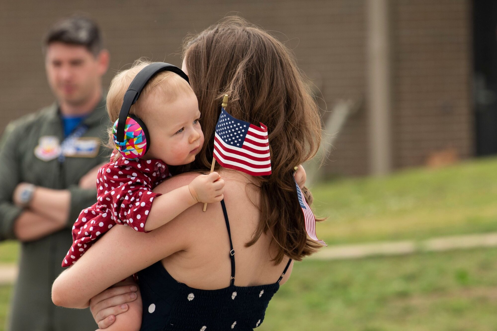 Photo of a Team Shaw spouse holding her baby who is holding a U.S. flag.