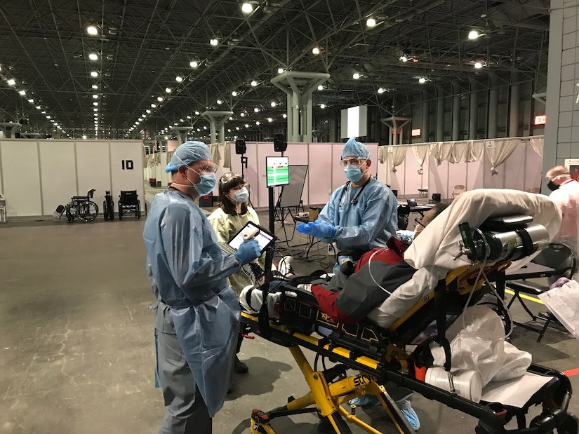 People wearing personal protective equipment check in a patient.