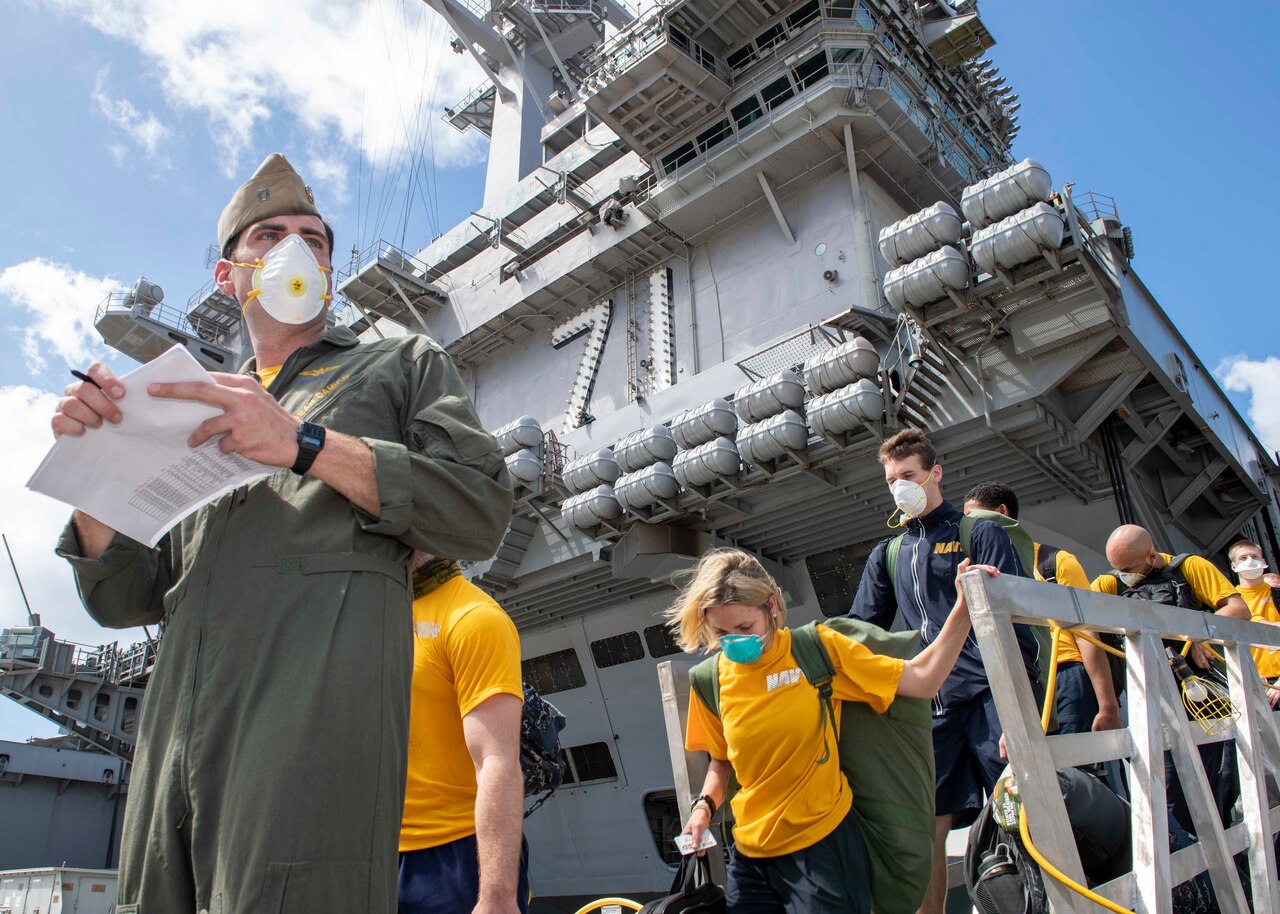 Sailors wearing masks disembark from a ship.