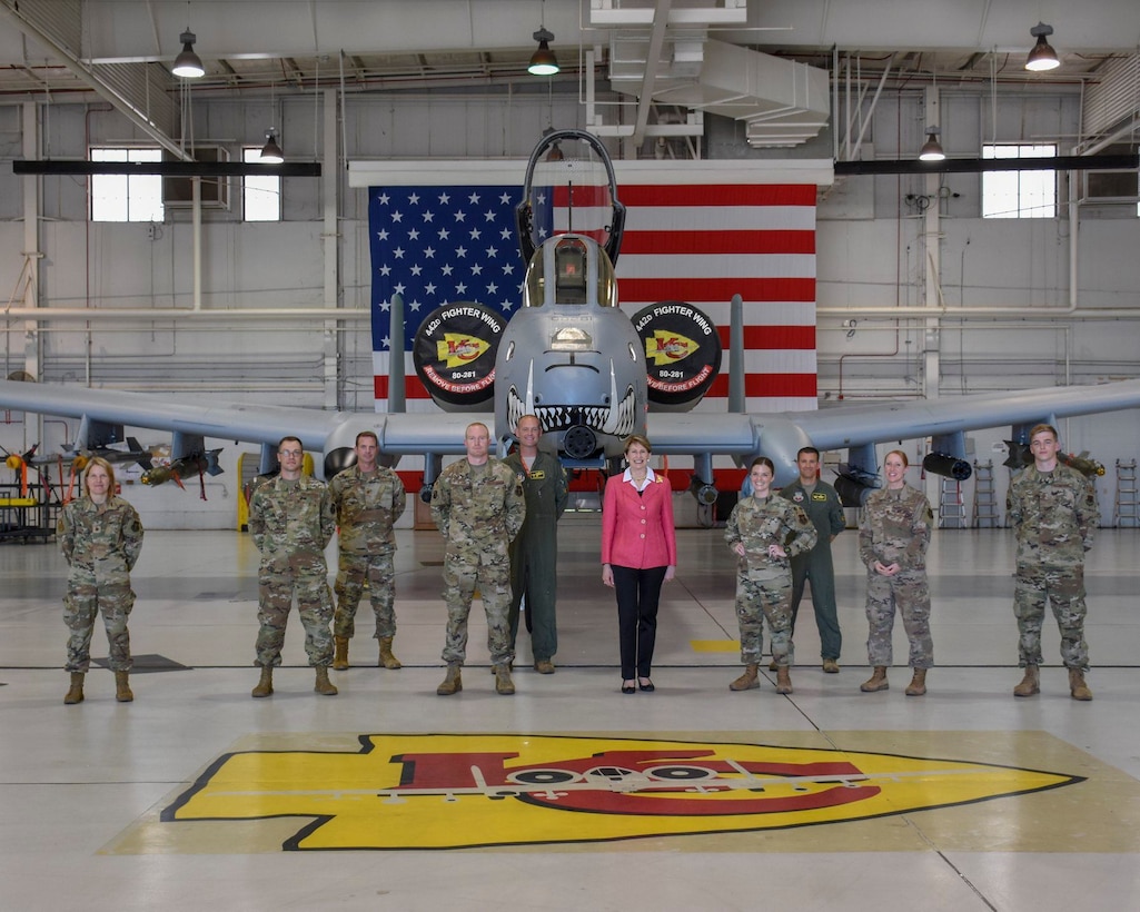Nine Airmen pose in front of an A-10 Thunderbolt II attack aircraft with the 25th Secretary of the Air Force Barbara M. Barrett.