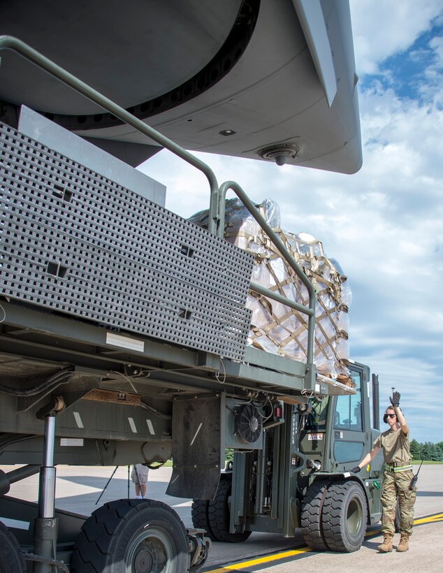 U.S. Air Force Tech. Sgt. Heather Boutin works with an Senior Airman Megan Lenling, both Air Transportation Specialists with the 133rd Airlift Wing’s Air Transportation Function to direct and onload palletized cargo from a forklift onto a C-17 Globemaster III during a recent Denton Humanitarian Assistance Program mission in St. Paul, Minn., June 13, 2020.