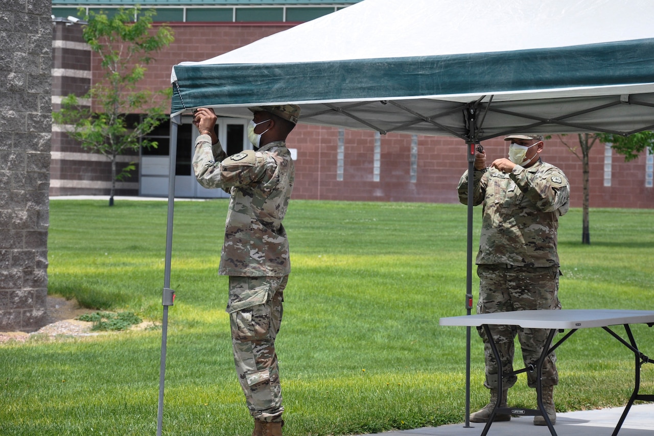 Two soldiers set up a canopy.