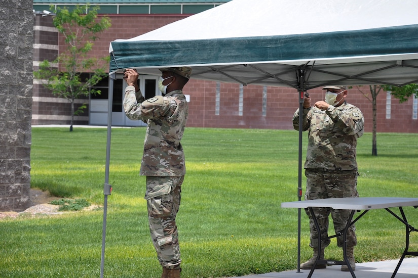 Two soldiers set up a canopy.