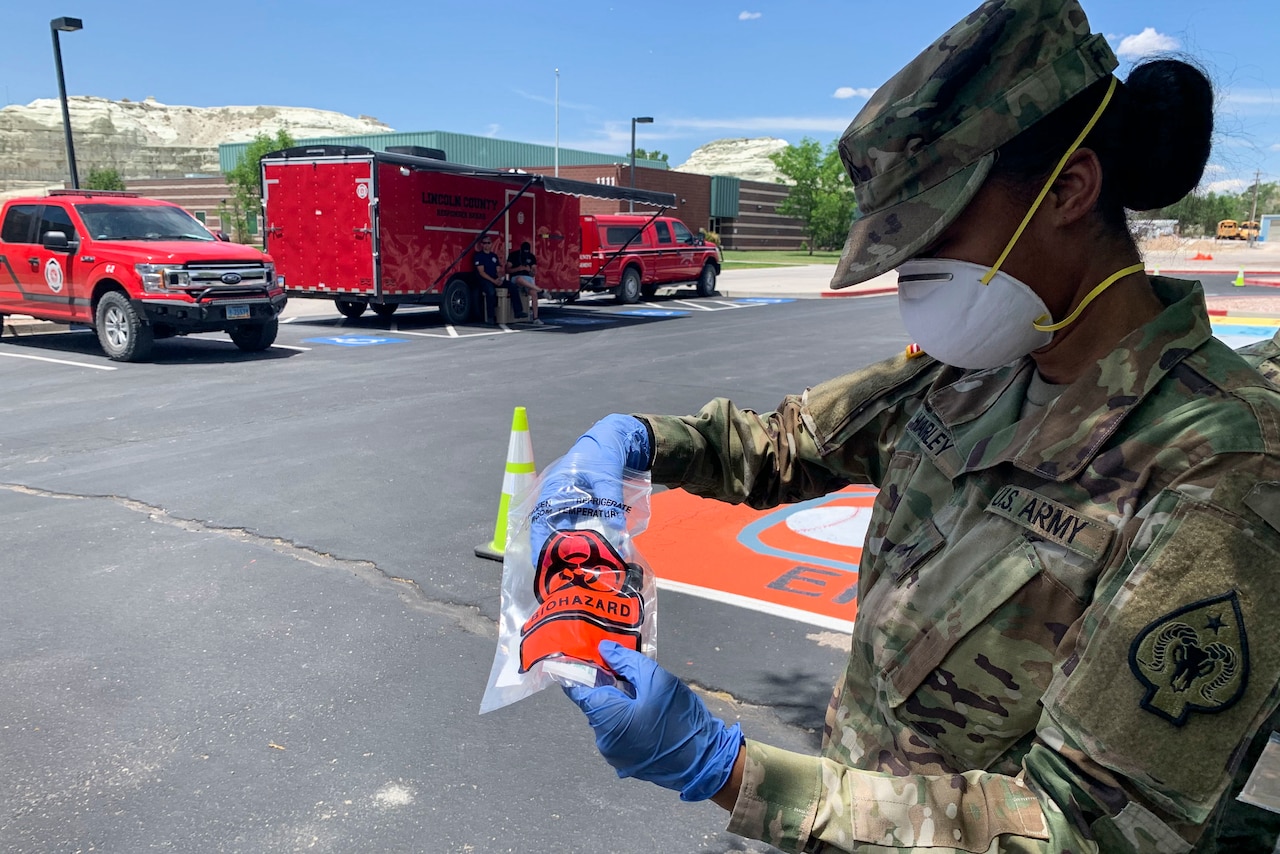 A soldier removes a COVID-19 test kit from a plastic bag.