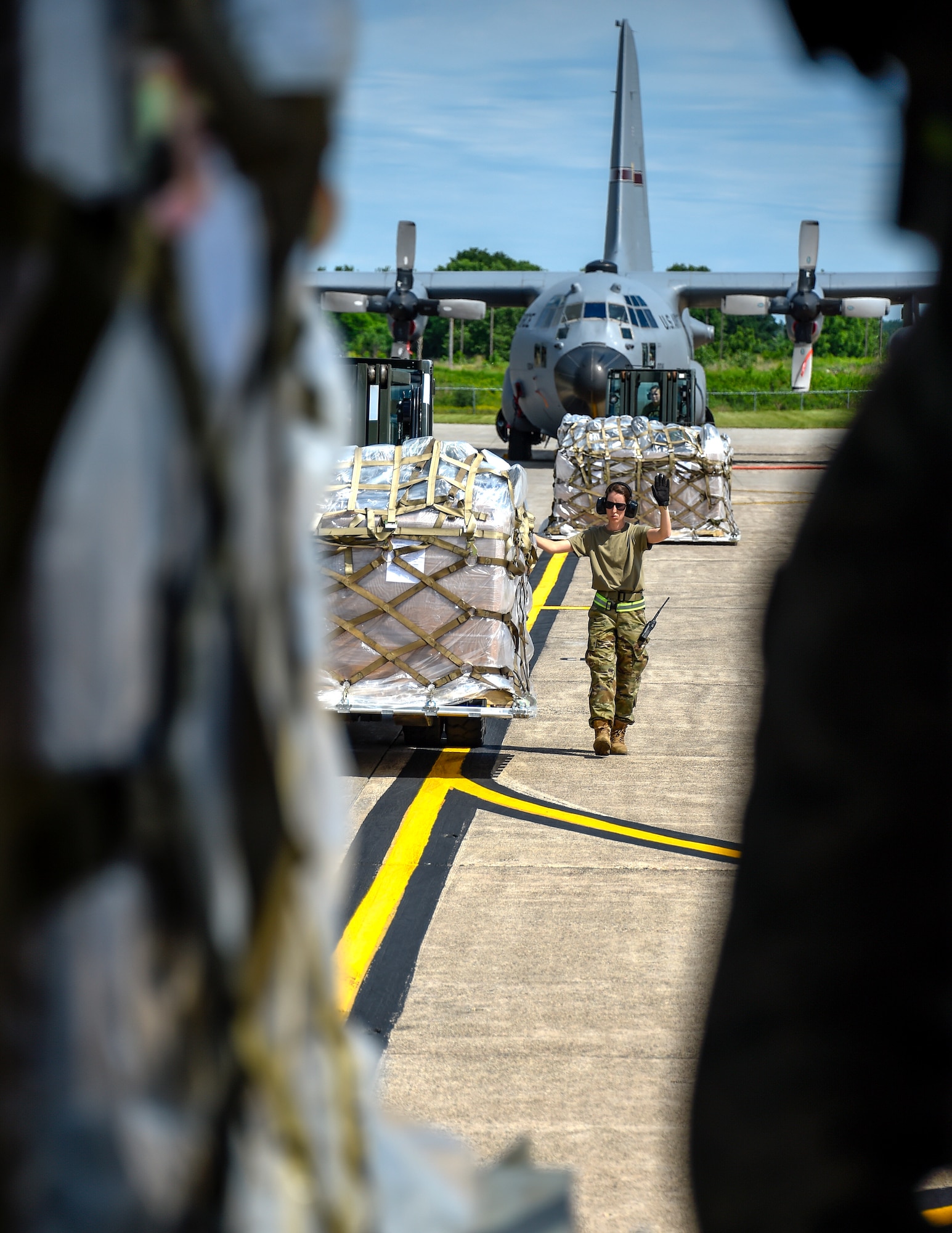 U.S. Air Force Tech. Sgt. Heather Boutin works with an Senior Airman Megan Lenling, both Air Transportation Specialists with the 133rd Airlift Wing’s Air Transportation Function to direct and onload palletized cargo from a forklift onto a C-17 Globemaster III during a recent Denton Humanitarian Assistance Program mission in St. Paul, Minn., June 13, 2020.