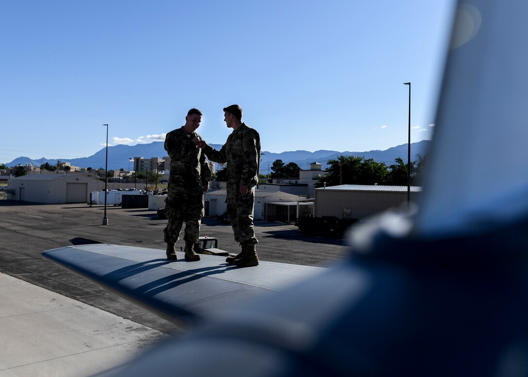 Airmen stand on an aircraft.