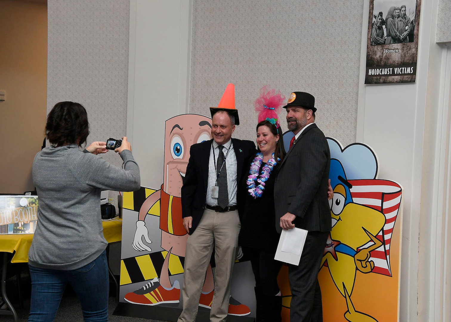 Don Phillips, left, director for DLA Installation Management at Battle Creek, Michigan, and DLA Disposition Services Director Mike Cannon, right, have some fun with Voluntary Protection Program team member Lyndi Brown at the 2019 Spring Into Safety photo booth.