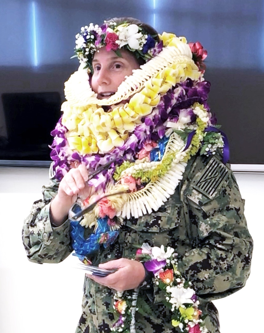 Female Navy captain poses with several leis given to her by DLA Indo-Pacific employees.