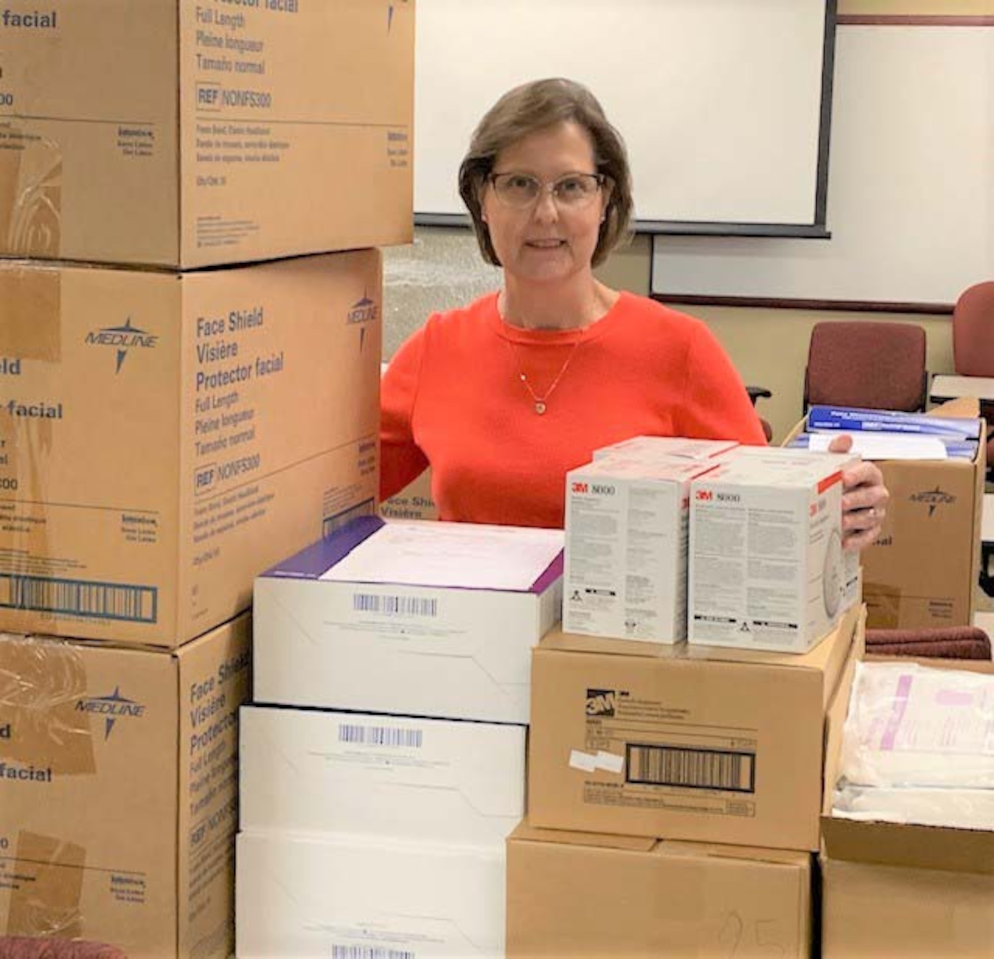 Photo of female Air Force Reservist standing behind boxes of personal protective equipment.