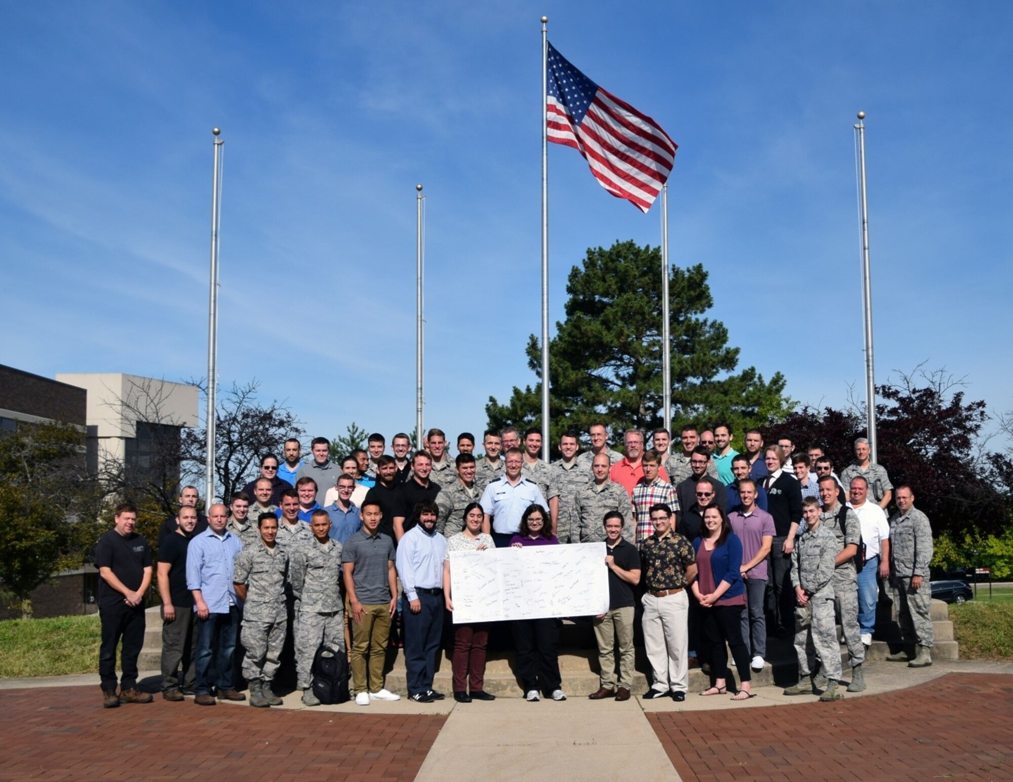 group of people stand at base of flag