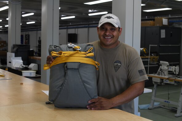 U.S. Air Force Tech. Sgt. Daniel Quintana, 57th Rescue Squadron Parachute NCOIC, poses with a parachute he packed May 27, 2020, at Aviano Air Base, Italy. Quintana has been a rigger for ten years. (U.S. Air Force photo by Senior Airman Caleb House)