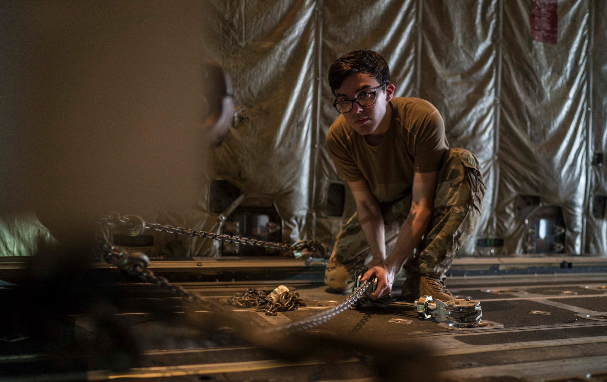 U.S. Air Force Senior Airman Tyler Scott, 75th Expeditionary Airlift Squadron (EAS) loadmaster, chains down cargo on board a C-130J Super Hercules at Camp Lemonnier, Djibouti, June 6, 2020. The 75th EAS provides strategic Airlift capabilities across the Combined Joint Task Force - Horn of Africa (CJTF-HOA) area of responsibility. (U.S. Air Force photo by Staff Sgt. Shawn White)