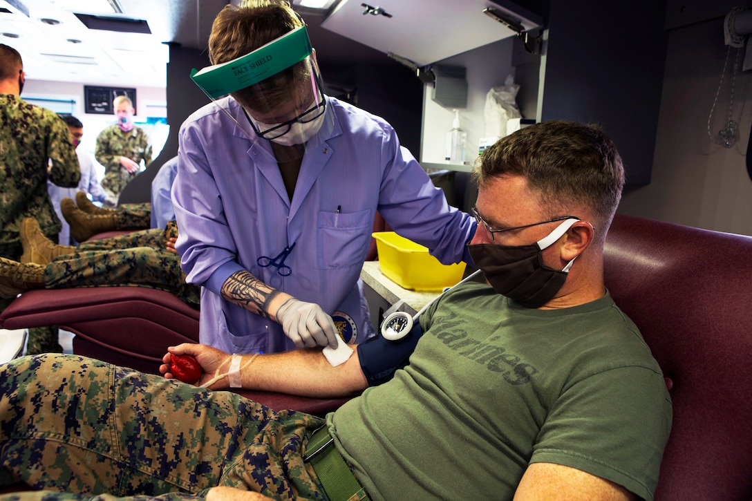 A Marine wearing a mask is tested by medical personnel wearing personal protective equipment.