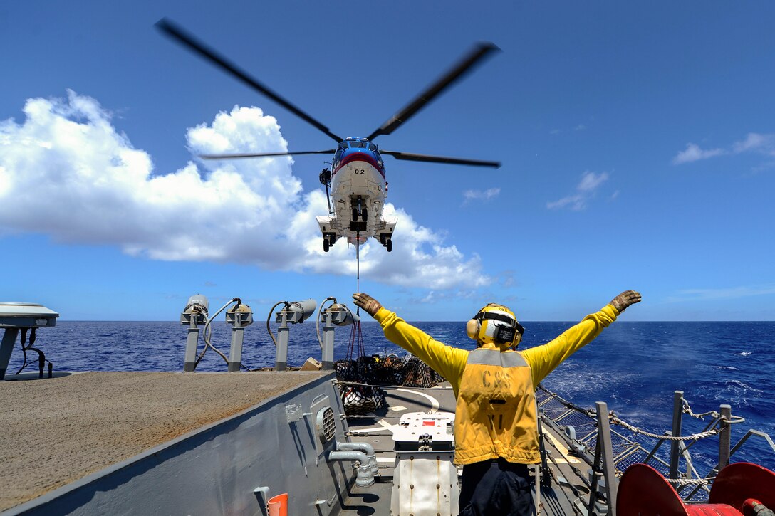 A sailor signals the pilot of a helicopter.