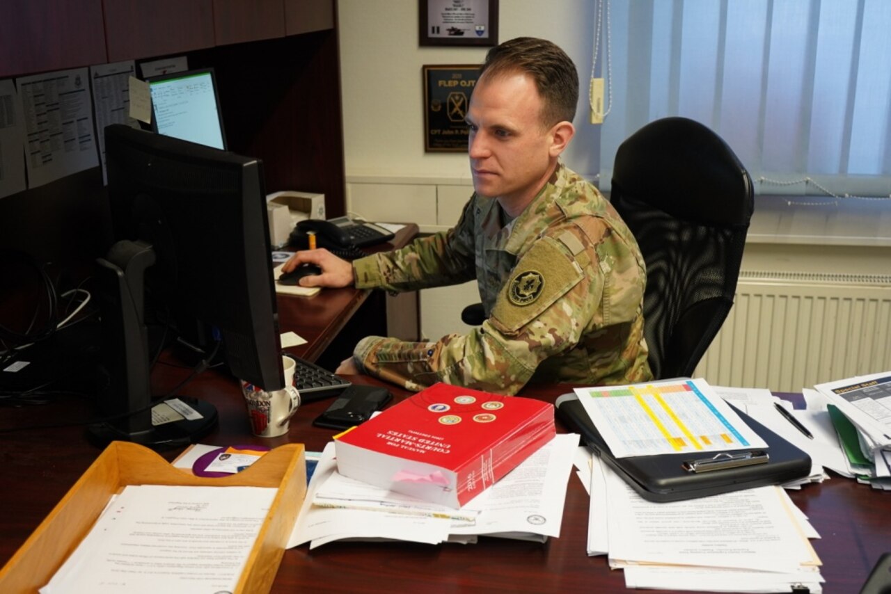 A military lawyer works at a desktop computer.