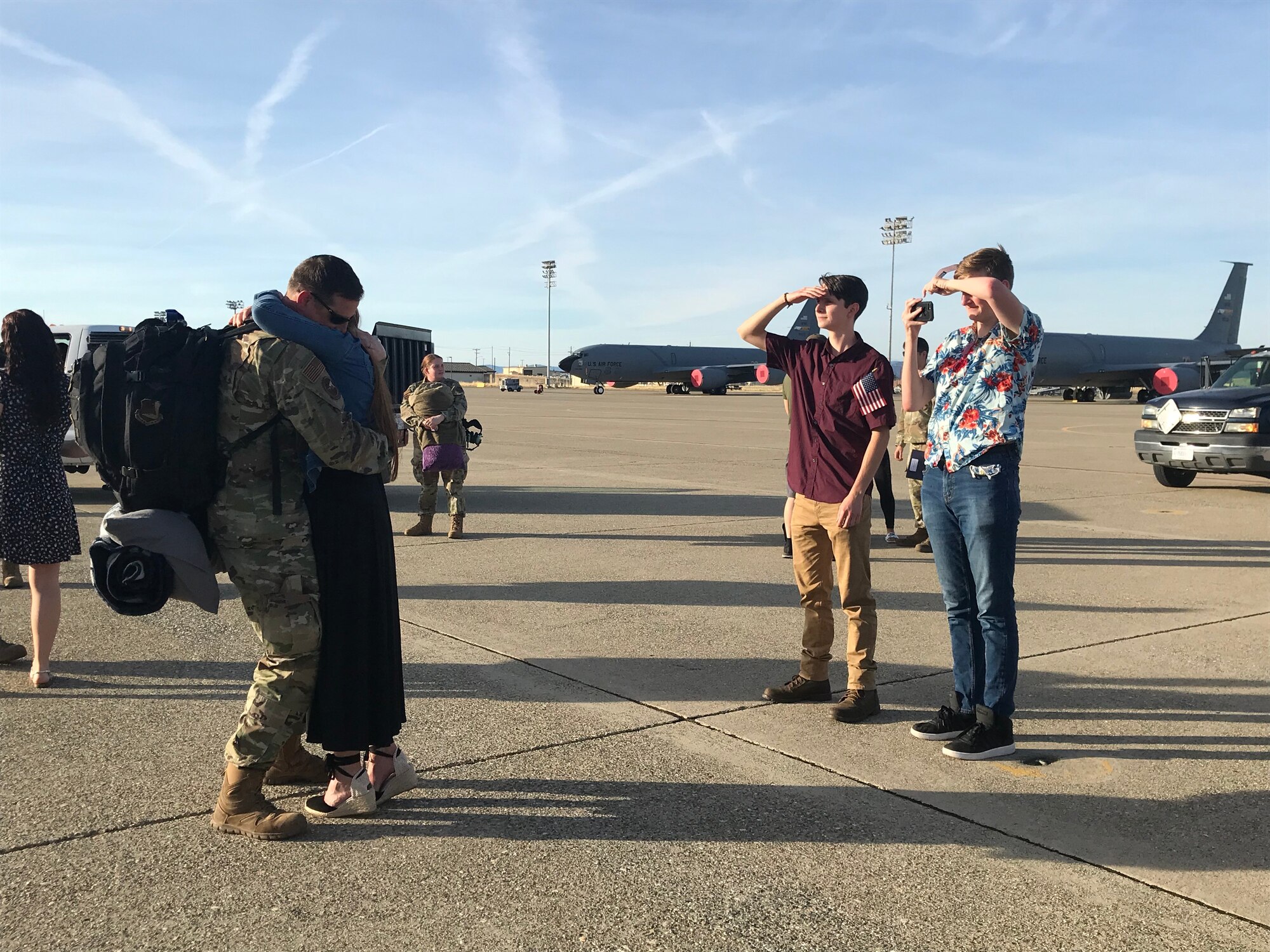 An Airman from the 940th Air Refueling Wing hugs his loved one, while two men continue to wait for their family member to arrive home from deployment June 14, 2020, at Beale Air Force Base, California.
