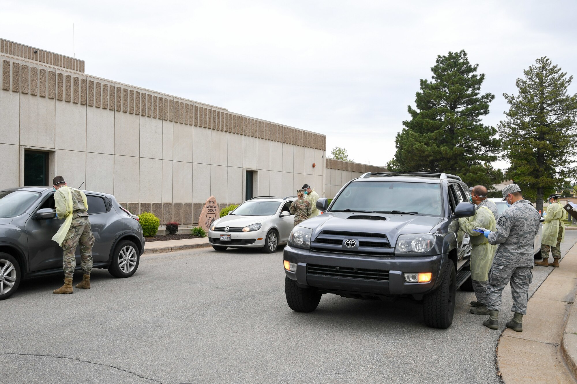 Airmen wait in their cars for a drive-up medical screening and COVID-19.