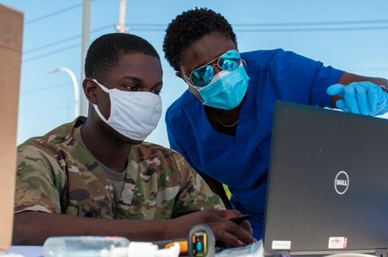 Spc. Kwabena Anim-Appiah and Sgt. Carlene McKenzie, combat medics with the Delaware Army National Guard, wear personal protective equipment at a drive-thru testing site for COVID-19 on the University of Delaware's Science, Technology and Advanced Research Campus in Newark, Delaware, June 12, 2020. About 25 soldiers and airmen with the National Guard supported the saliva-based testing of 950 people at the STAR Campus location.