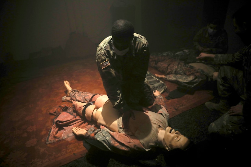 A soldier practices administering CPR on a mannequin.