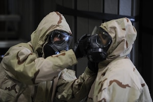 Tech. Sgt. Javier Mendoza, 940th Air Refueling Wing ground transport technician, and Staff Sgt. Jazmyn Sumrall-McCavley, 940th Logistics Readiness Squadron distribution operations technician, assist each other in securing the chemical, biological, radiological and nuclear overcoat hood to the M50 gas mask June 13, 2020, at Beale Air Force Base, California.