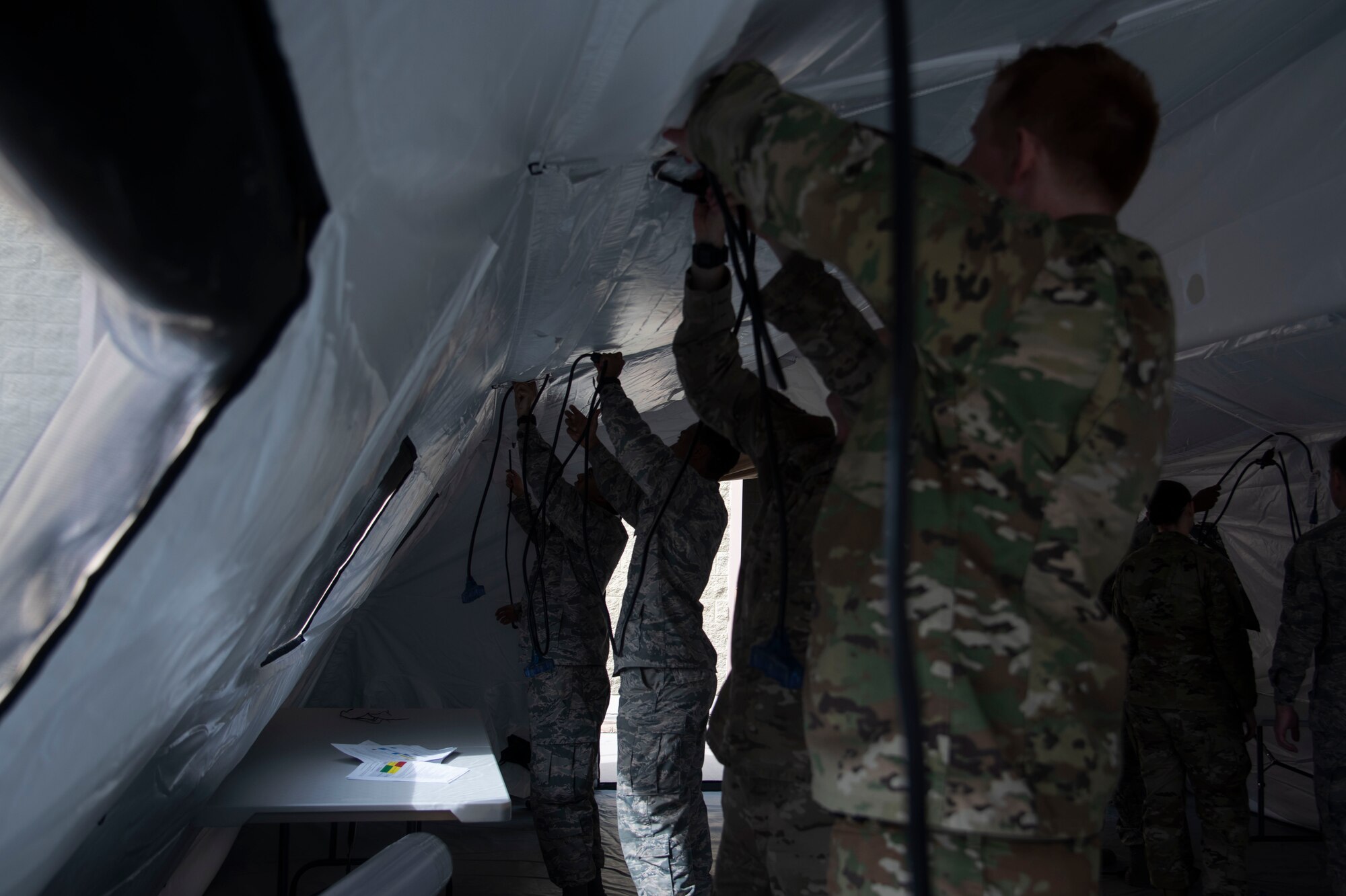 366th Fighter Wing A2 (Intell) Airmen line the ceiling of the TM60 tent with power cables, June 3, 2020, on Mountain Home Air Force Base, Idaho,. A fully functional Agile Combat Employment Mission Planning Cell will include computers with full internet access and an heating ventalation and air conditioning system. (U.S. Air Force photo by Airman 1st Class Nicholas Swift)