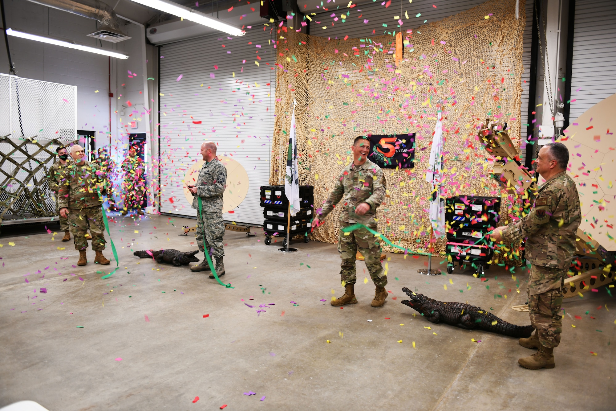 Photo shows Airmen cutting a ribbon with confetti falling from above.