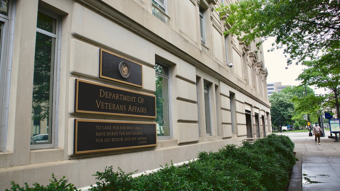 A man wearing a protective mask walks in front of the Department of Veterans Affairs headquarters building in Washington, D.C., on May 28, 2020. The VA recently released guidelines for forbearance relief options available to homeowners struggling with mortgage payments due to a Coronavirus-related hardship. (U.S. Air Force photo by Master Sgt. Stephen J. Caruso)
