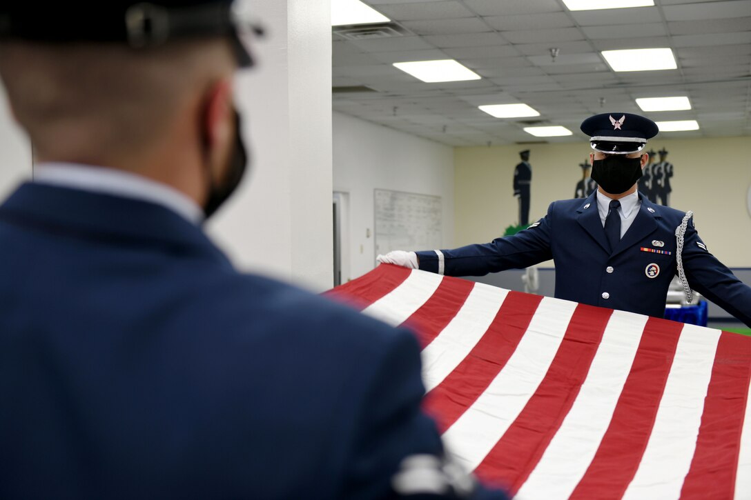 Photo shows two Honor Guard members pulling a flag straight between them.