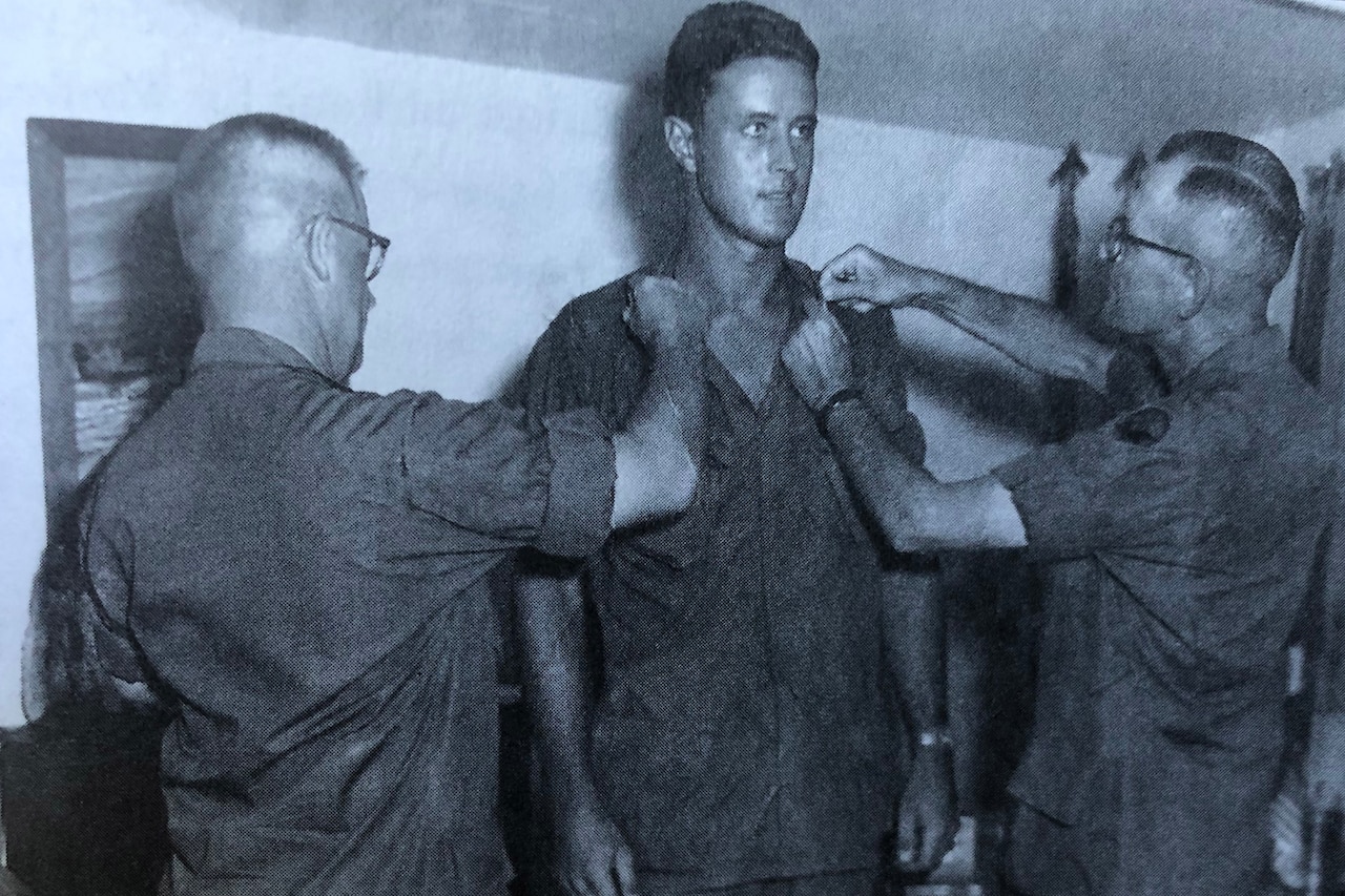 Three men participate in a promotion ceremony.